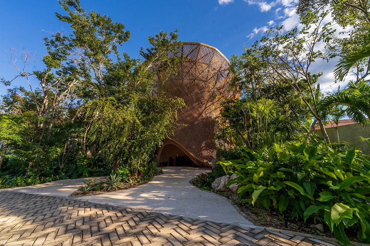 Sculptural timber building surrounded by tropical gardens and stone paths — Aflora 214