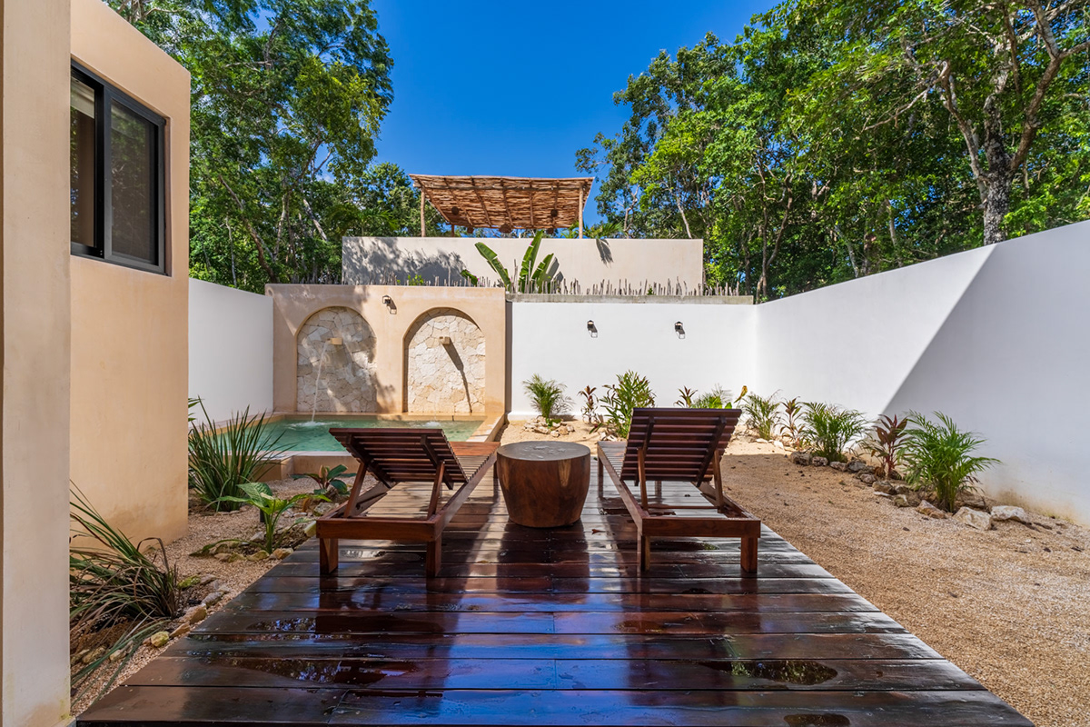 Private courtyard pool with wooden loungers and tropical planting — Surenna 21
