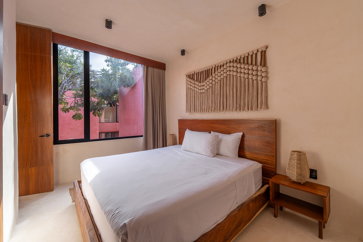 Bedroom with a wooden headboard and a window overlooking the courtyard — Tulix 8